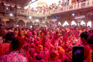 MATHURA, UTTAR PRADESH, INDIA - 2024/03/17: Hindu devotees play with colorful powders (Gulal) during the Laddu Holi celebrations at the Radharani temple of Barssana - Uttar Pradesh. The spring festival of colors at Radharani temple in Barsana village of India's Uttar Pradesh is the first day of the Celebration of the main Holi Festival. At this festival the devotees and priests of Barsana Temple throw Laddu (Traditional Sweet) on each other. Holi is a spring festival also known as the festival of colors or the festival of love.